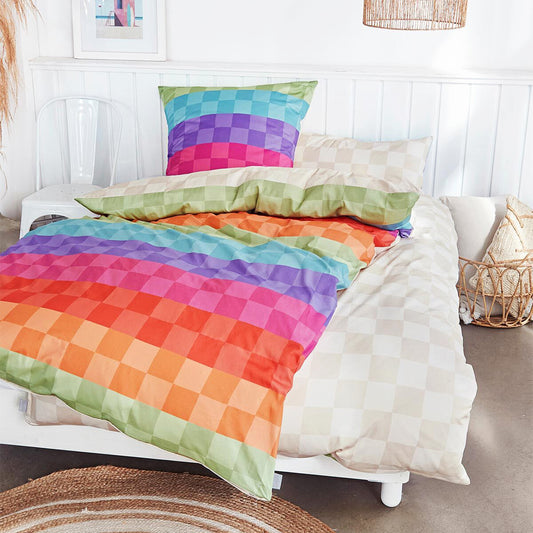 Auf einem Bett liegen mehrere Kopfkissen und eine Bettdecke bezogen mit Mako-Satin Bettwaesche aus 100 Prozent Baumwolle mit Muster aus Quadraten in der Farbe Mehrfarbig. Modell Puwei.