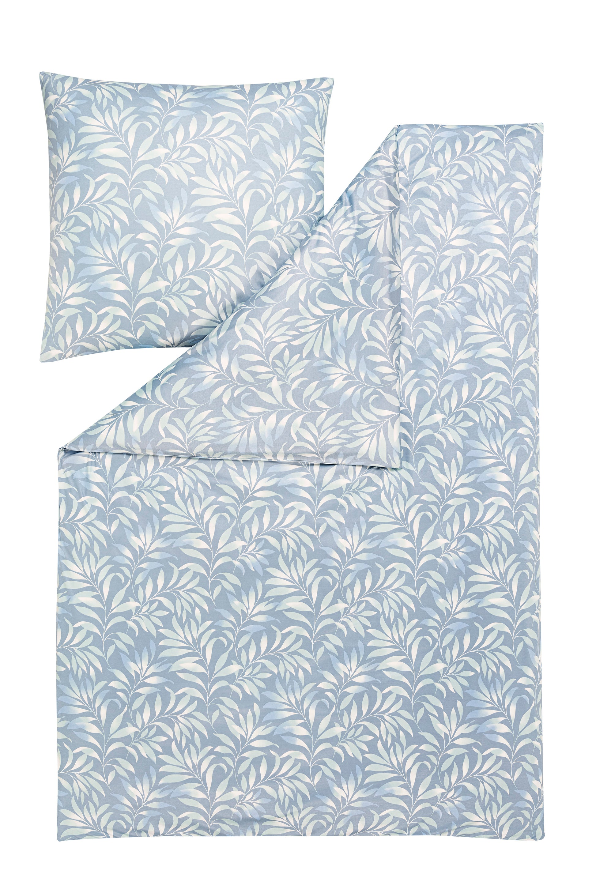 Ein Kopfkissen und eine Bettdecke bezogen mit Mako-Interlock-Jersey Bettwaesche mit einem Muster aus Blaettern in der Farbe Blau. Modell Elif Taube.