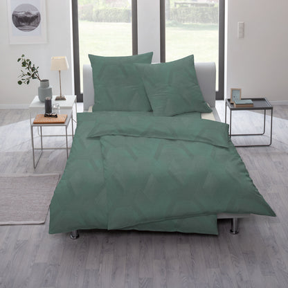 Ein Bettbezug-Set aus mehreren Kopfkissen und einer Bettdecke bezogen mit Mako-Interlock-Jersey Bettwaesche aus 100 Prozent Baumwolle mit Muster aus Rauten in der Farbe Gruen. Modell Emerald.