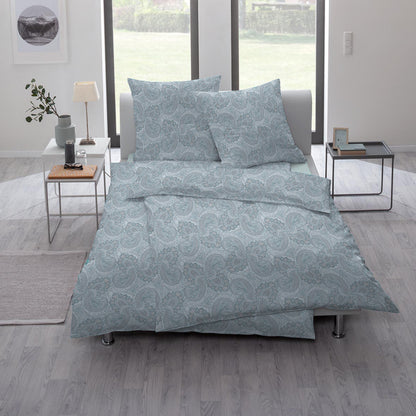 Ein Bettbezug-Set aus mehreren Kopfkissen und einer Bettdecke bezogen mit Mako-Interlock-Jersey Bettwaesche aus 100 Prozent Baumwolle mit Muster aus Ornamenten in der Farbe Blau. Modell Lipari.