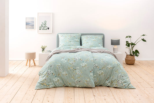Ein Bettbezug-Set aus mehreren Kopfkissen und einer Bettdecke bezogen mit Mako-Interlock-Jersey Bettwaesche aus 100 Prozent Baumwolle mit Muster aus Blumen in der Farbe Mint. Modell Minou.