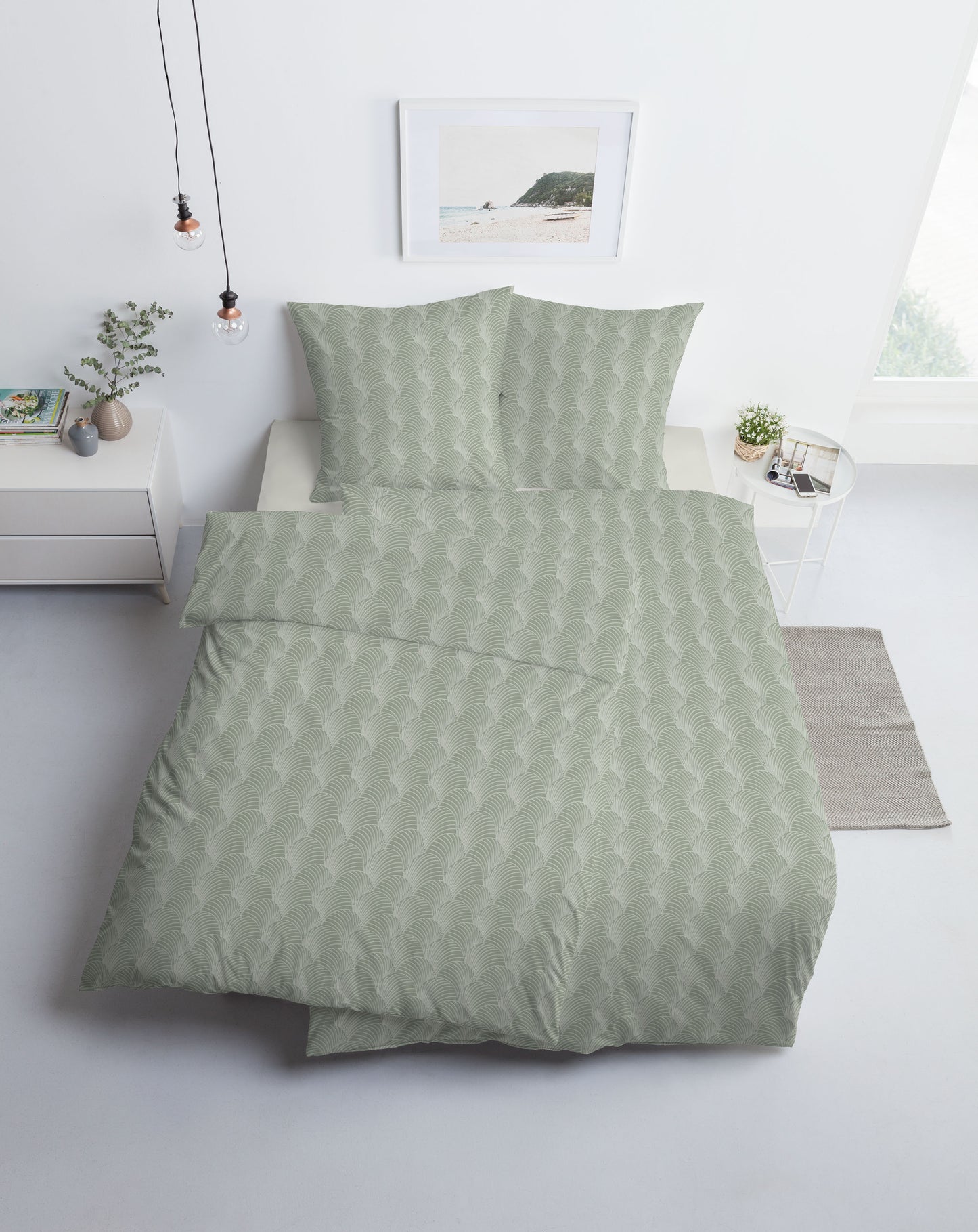 Ein Bettbezug-Set aus mehreren Kopfkissen und einer Bettdecke bezogen mit Mako-Interlock-Jersey Bettwaesche aus 100 Prozent Baumwolle mit Muster aus Muschel-Linien in der Farbe Gruen. Modell Pianosa.