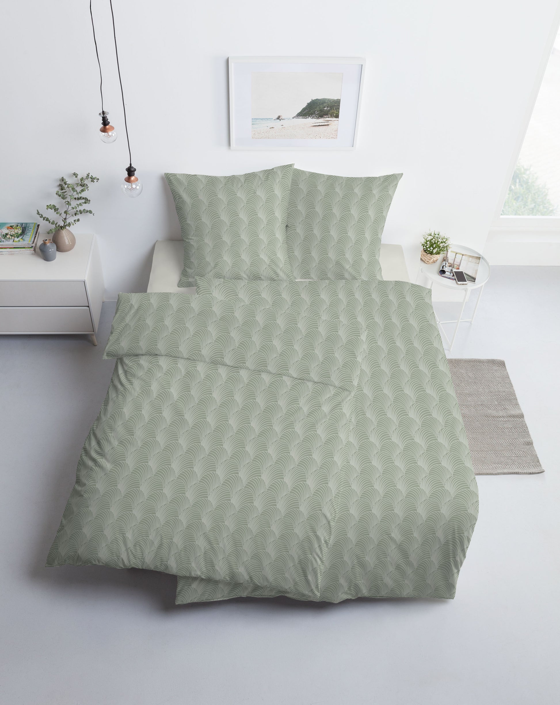 Ein Bettbezug-Set aus mehreren Kopfkissen und einer Bettdecke bezogen mit Mako-Interlock-Jersey Bettwaesche aus 100 Prozent Baumwolle mit Muster aus Muschel-Linien in der Farbe Gruen. Modell Pianosa.