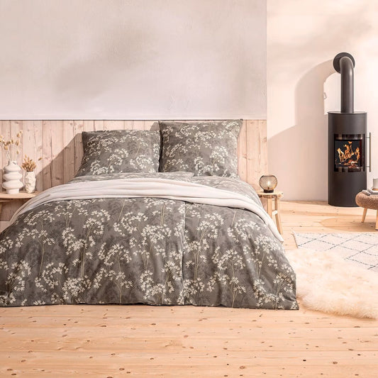 Ein Bettbezug-Set aus mehreren Kopfkissen und einer Bettdecke bezogen mit Mako-Interlock-Jersey Bettwaesche aus 100 Prozent Baumwolle mit Muster aus Blueten in der Farbe Beige. Modell Riona Beige.