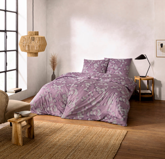 Ein Bettbezug-Set aus mehreren Kopfkissen und einer Bettdecke bezogen mit Mako-Interlock-Jersey Bettwaesche aus 100 Prozent Baumwolle mit Muster aus Blueten in der Farbe Rosa. Modell Rumi Mauve.