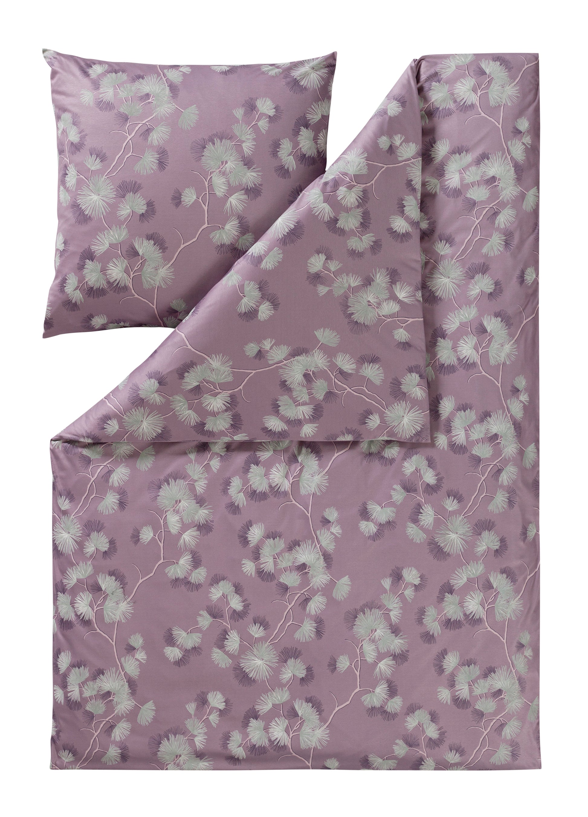 Ein Kopfkissen und eine Bettdecke bezogen mit Mako-Interlock-Jersey Bettwaesche mit einem Muster aus Blueten in der Farbe Rosa. Modell Rumi Mauve.
