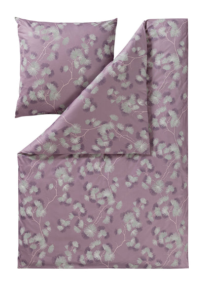 Ein Kopfkissen und eine Bettdecke bezogen mit Mako-Interlock-Jersey Bettwaesche mit einem Muster aus Blueten in der Farbe Rosa. Modell Rumi Mauve.