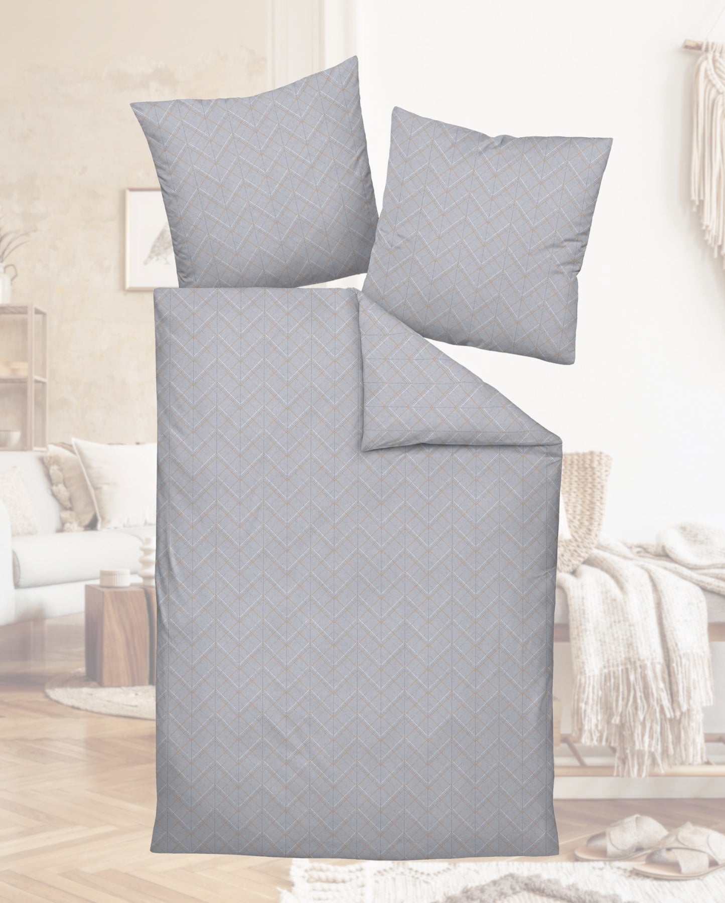 Auf einem Bett liegen mehrere Kopfkissen und eine Bettdecke bezogen mit Mako-Satin Bettwaesche aus 100 Prozent Baumwolle mit Muster aus grafischen Formen in der Farbe Grau. Modell Milano Geometric Grey.