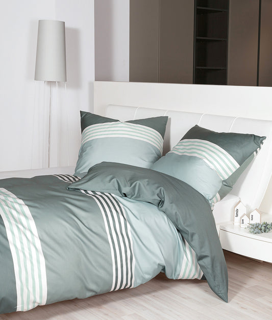 Auf einem Bett liegen mehrere Kopfkissen und eine Bettdecke bezogen mit Mako-Satin Bettwaesche aus 100 Prozent Baumwolle mit Muster aus horizontalen Streifen in der Farbe Mint. Modell Palermo Lineo.