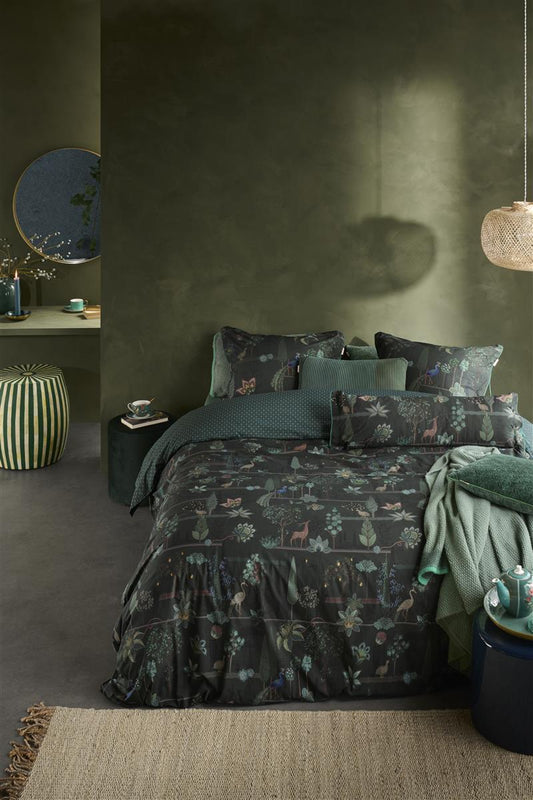 Auf einem Bett liegen mehrere Kopfkissen und eine Bettdecke bezogen mit Perkal-Baumwoll Bettwaesche aus 100 Prozent Baumwolle mit Muster aus Tieren und Pflanzen in der Farbe Gruen. Modell Alberi Dunkelgruen.