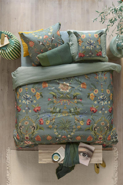 Auf einem Bett liegen mehrere Kopfkissen und eine Bettdecke bezogen mit Perkal-Baumwoll Bettwaesche aus 100 Prozent Baumwolle mit Muster aus Pflanzen und Tieren in der Farbe Petrol. Modell Botanico Verde Blau.