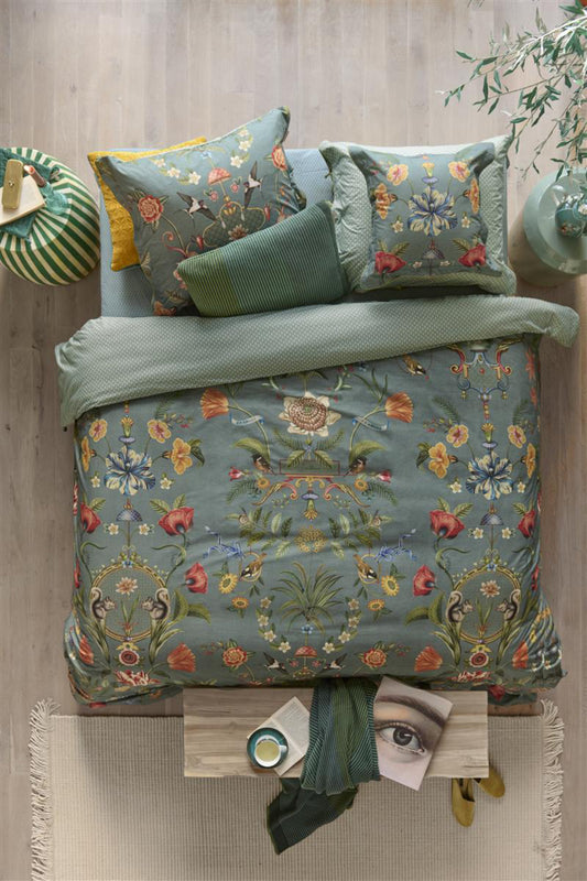 Auf einem Bett liegen mehrere Kopfkissen und eine Bettdecke bezogen mit Perkal-Baumwoll Bettwaesche aus 100 Prozent Baumwolle mit Muster aus Pflanzen und Tieren in der Farbe Petrol. Modell Botanico Verde Blau.