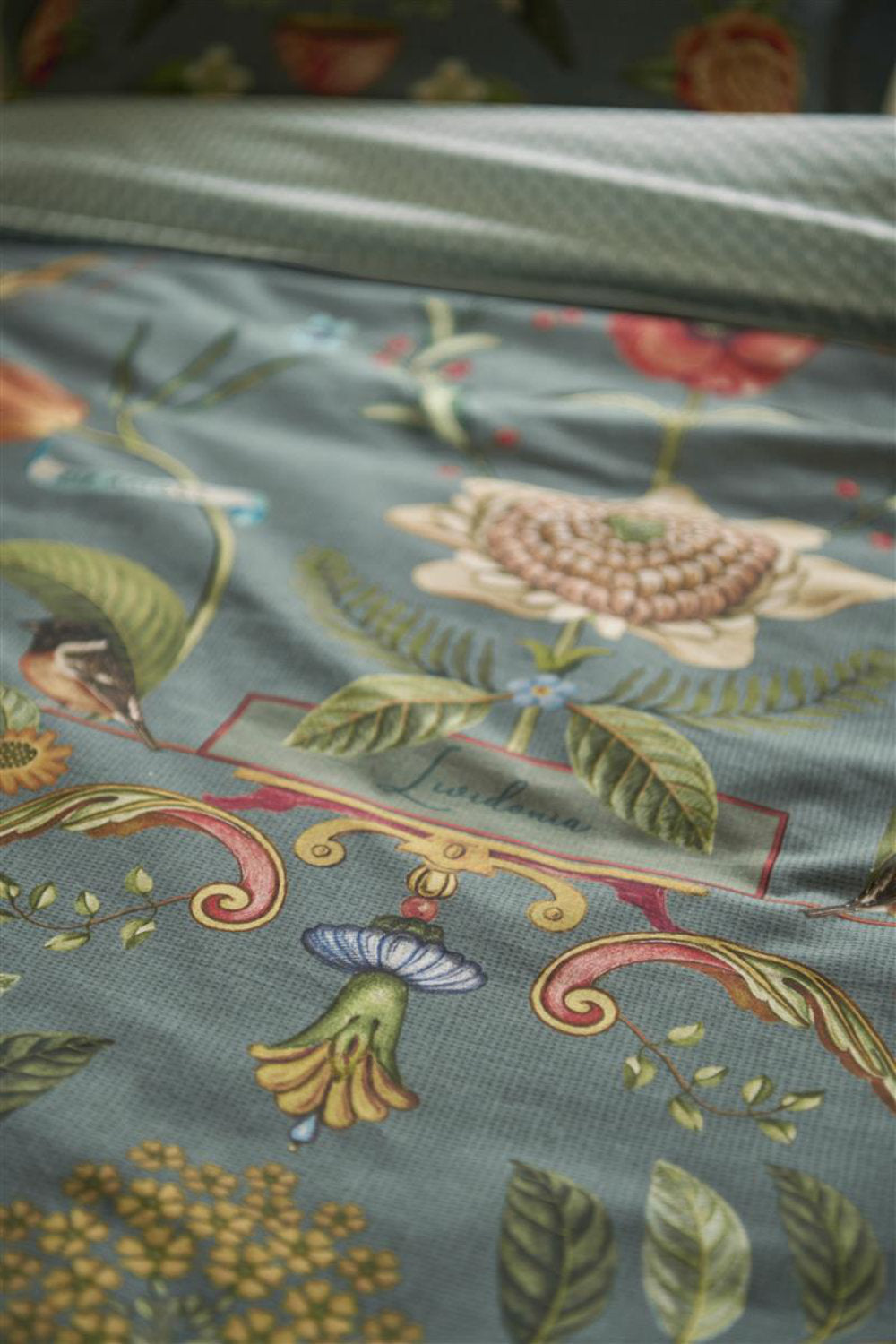 Detaildarstellung der Pflanzen und Tiere und grafischen Formen auf Kopfkissen und Bettdecke der Perkal-Baumwoll Bettwaesche Modell Botanico Verde Blau.