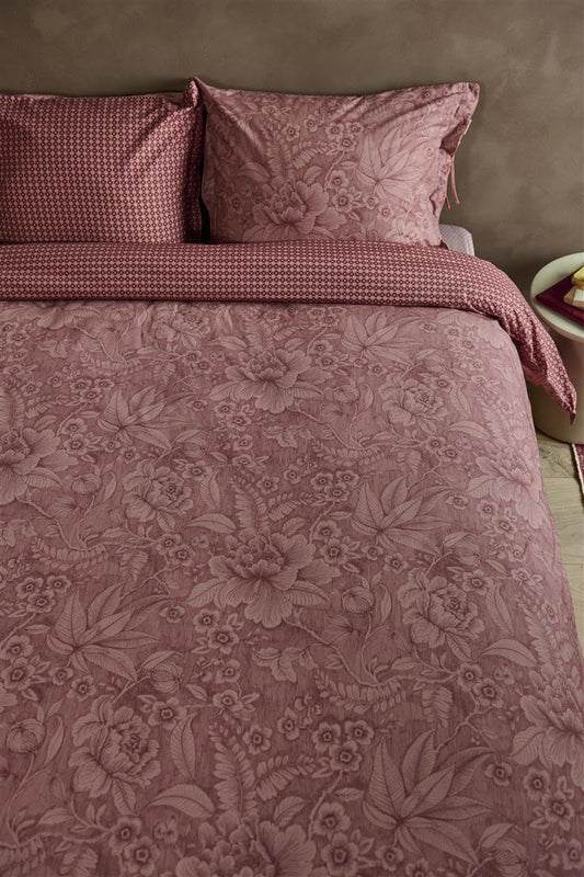 Auf einem Bett liegen mehrere Kopfkissen und eine Bettdecke bezogen mit Perkal-Baumwoll Bettwaesche aus 100 Prozent Baumwolle mit Muster aus Blumen und grafischen Formen in der Farbe Roségold. Modell Casa Dei Fiori Terrakotte.