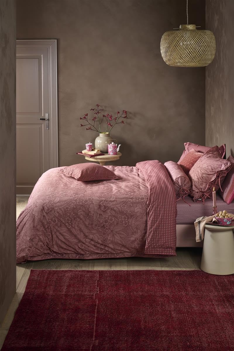Ein Bettbezug-Set aus mehreren Kopfkissen und einer Bettdecke bezogen mit Perkal-Baumwoll Bettwaesche aus 100 Prozent Baumwolle mit Muster aus Blumen und grafischen Formen in der Farbe Roségold. Modell Casa Dei Fiori Terrakotte.