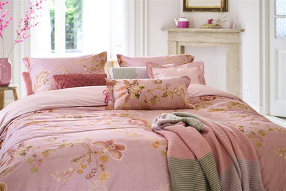 Auf einem Bett liegen mehrere Kopfkissen und eine Bettdecke bezogen mit Perkal-Baumwoll Bettwaesche aus 100 Prozent Baumwolle mit Muster aus Blumen und grafischen Formen in der Farbe Rosa. Modell Cece Fiore Rosa.