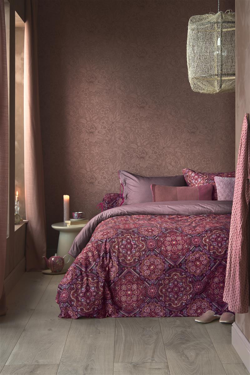 Auf einem Bett liegen mehrere Kopfkissen und eine Bettdecke bezogen mit Perkal-Baumwoll Bettwaesche aus 100 Prozent Baumwolle mit Muster aus Pflanzen in der Farbe Roségold. Modell Il Musaico Dark Red.