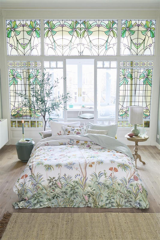 Auf einem Bett liegen mehrere Kopfkissen und eine Bettdecke bezogen mit Perkal-Baumwoll Bettwaesche aus 100 Prozent Baumwolle mit Muster aus Pflanzen und Voegeln in der Farbe Weiss. Modell Il Paradiso Weiss.
