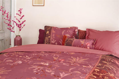 Ein Bettbezug-Set aus mehreren Kopfkissen und einer Bettdecke bezogen mit Perkal-Baumwoll Bettwaesche aus 100 Prozent Baumwolle mit Muster aus Pflanzen in der Farbe Pink. Modell Isola Pink.