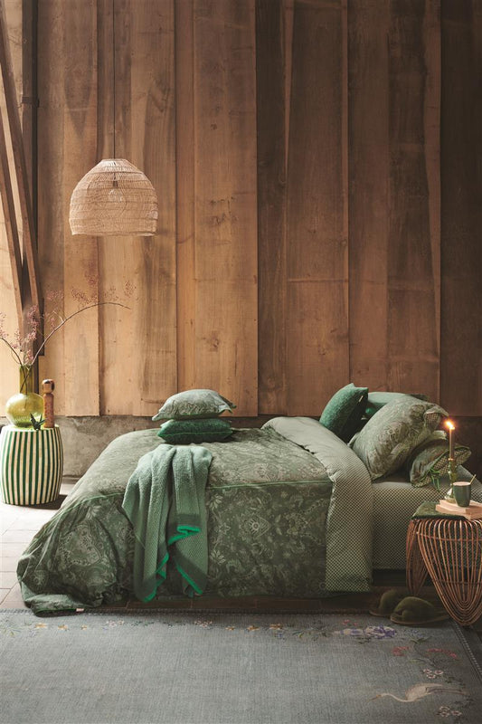 Auf einem Bett liegen mehrere Kopfkissen und eine Bettdecke bezogen mit Perkal-Baumwoll Bettwaesche aus 100 Prozent Baumwolle mit Muster aus Ornamenten in der Farbe Gruen. Modell Kyoto Nights Green.