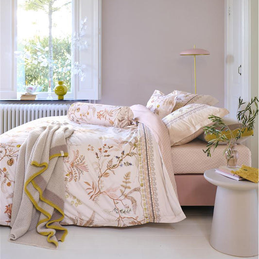 Auf einem Bett liegen mehrere Kopfkissen und eine Bettdecke bezogen mit Perkal-Baumwoll Bettwaesche aus 100 Prozent Baumwolle mit Muster aus Pflanzen in der Farbe Rosa. Modell Salento Off-White.