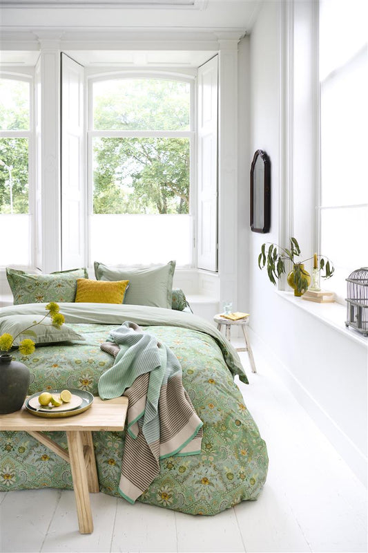 Auf einem Bett liegen mehrere Kopfkissen und eine Bettdecke bezogen mit Perkal-Baumwoll Bettwaesche aus 100 Prozent Baumwolle mit Muster aus Blumen in der Farbe Gruen. Modell Saluti Piccoli Green.
