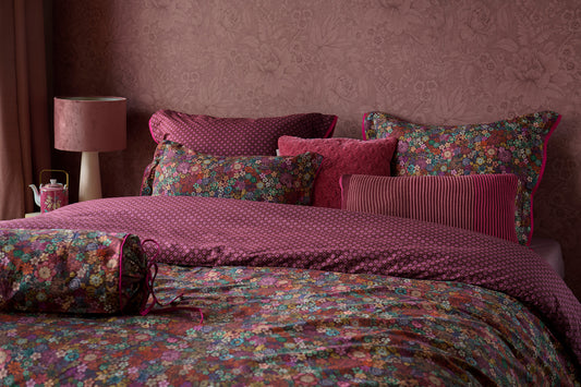 Auf einem Bett liegen mehrere Kopfkissen und eine Bettdecke bezogen mit Perkal-Baumwoll Bettwaesche aus 100 Prozent Baumwolle mit Muster aus Blumen in der Farbe Bordeaux. Modell Tutti i Fiori Dark Red.