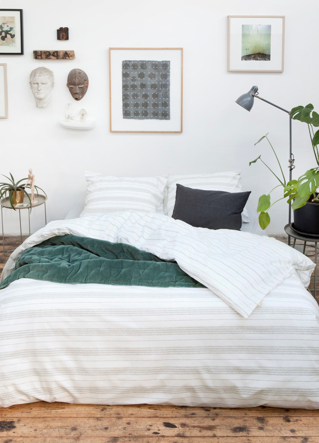 Auf einem Bett liegen mehrere Kopfkissen und eine Bettdecke bezogen mit Perkal-Baumwoll Bettwaesche aus 100 Prozent Baumwolle mit Muster aus horizontalen Streifen in der Farbe Weiss. Modell Head over Lines.