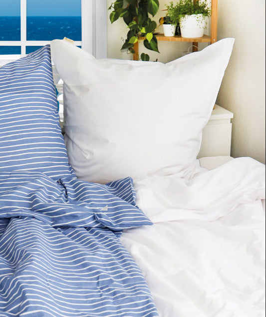 Auf einem Bett liegen mehrere Kopfkissen und eine Bettdecke bezogen mit Perkal-Baumwoll Bettwaesche aus 100 Prozent Baumwolle in der Farbe Weiss. Modell Hello New Day Weiß.