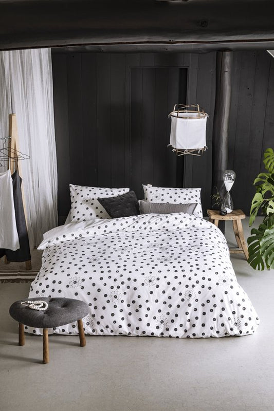 Auf einem Bett liegen mehrere Kopfkissen und eine Bettdecke bezogen mit Perkal-Baumwoll Bettwaesche aus 100 Prozent Baumwolle mit Muster aus Kreisen in der Farbe Weiss. Modell Silver Spots.