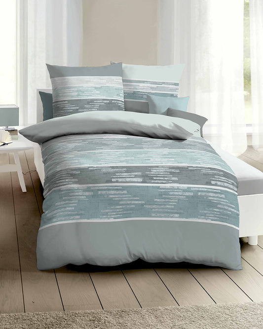 Auf einem Bett liegen mehrere Kopfkissen und eine Bettdecke bezogen mit Renforce Bettwaesche aus 100 Prozent Baumwolle mit Muster aus horizontalen Streifen in der Farbe Mint. Modell Stripe Mint.