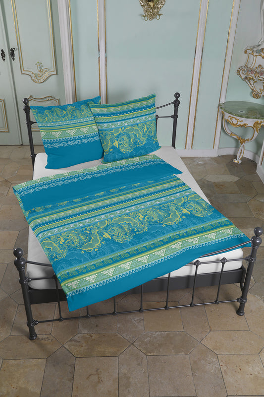 Mehrere Kopfkissen und eine Bettdecke bezogen mit seidig-weicher Satin Bettwaesche von Casatex mit einem Muster in der Farbe Tuerkis. Modell Kuala Lumpur Aqua-Gruen.