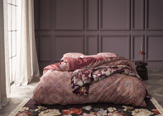 Ein Bettbezug-Set aus mehreren Kopfkissen und einer Bettdecke bezogen mit Satin Bettwaesche aus 100 Prozent Baumwolle mit Muster aus Ornamenten in der Farbe Roségold. Modell Boheme Rabarber.