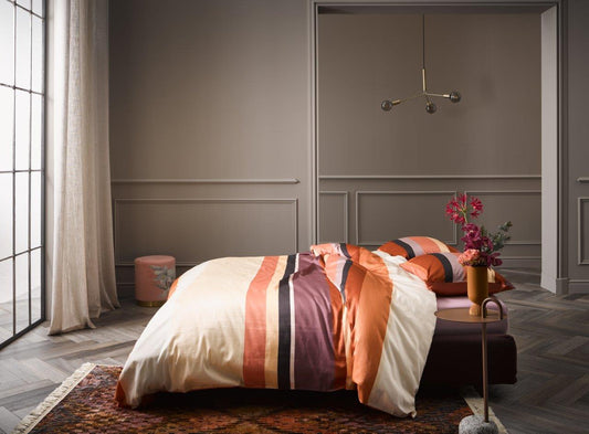 Ein Bettbezug-Set aus einem Kopfkissen und einer Bettdecke bezogen mit Satin Bettwaesche aus 100 Prozent Baumwolle mit Muster aus horizontalen Streifen in der Farbe Orange. Modell Edith Terra.