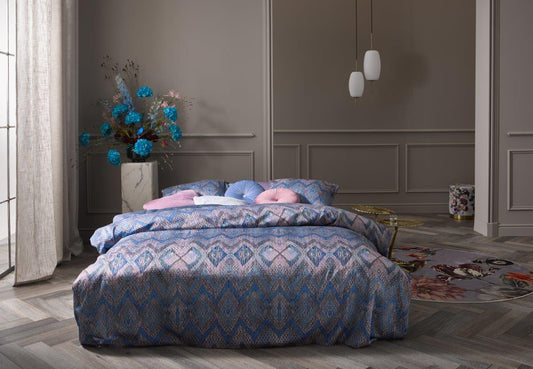 Ein Bettbezug-Set aus mehreren Kopfkissen und einer Bettdecke bezogen mit Satin Bettwaesche aus 100 Prozent Baumwolle mit Muster aus Linien in der Farbe Lila. Modell Fabienne Blue Granite.