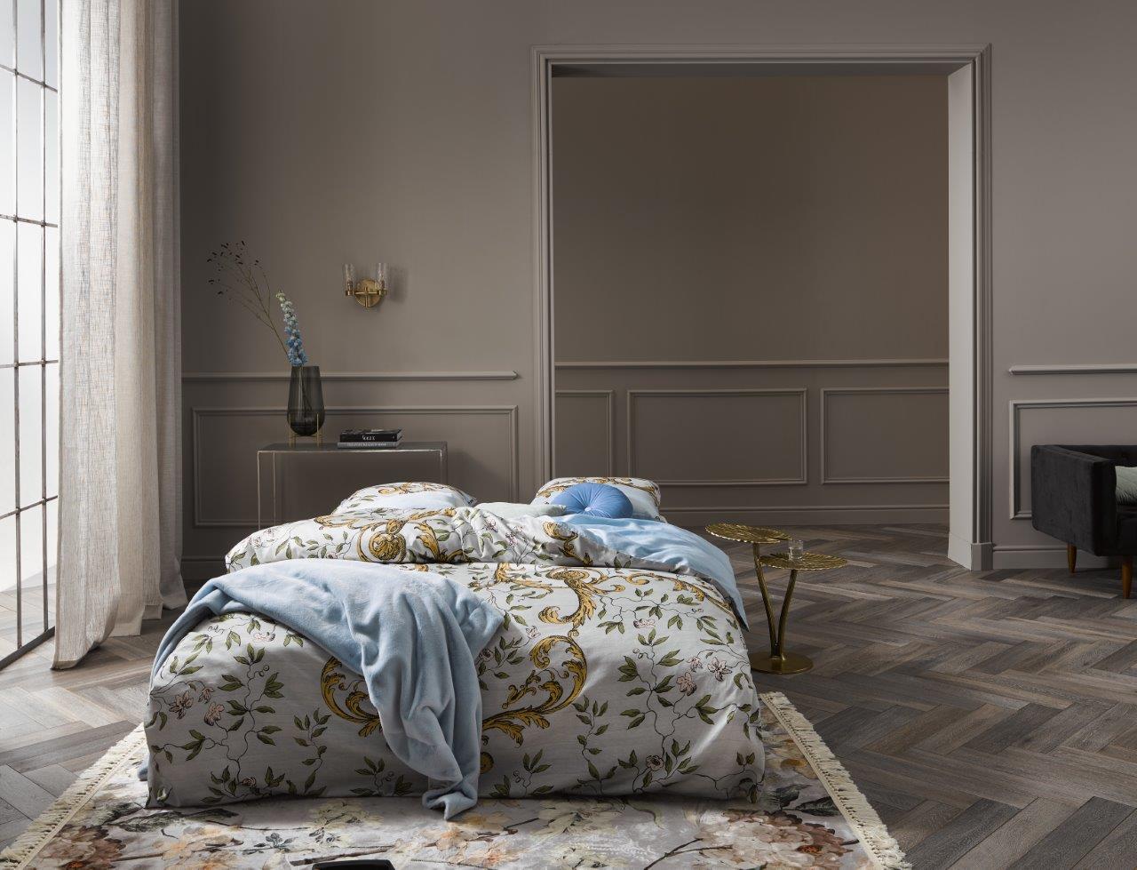 Ein Bettbezug-Set aus mehreren Kopfkissen und einer Bettdecke bezogen mit Satin Bettwaesche aus 100 Prozent Baumwolle mit Muster aus Zweigen und Blaettern in der Farbe Blau. Modell Georgina Iceblue.