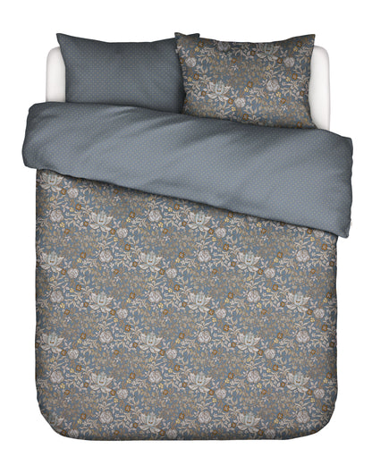 Zwei Kopfkissen und eine Bettdecke bezogen mit Satin Bettwaesche von Essenza mit einem Muster aus Blumen und Punkten in der Farbe Blau. Modell Ophelia Midnight Swim.