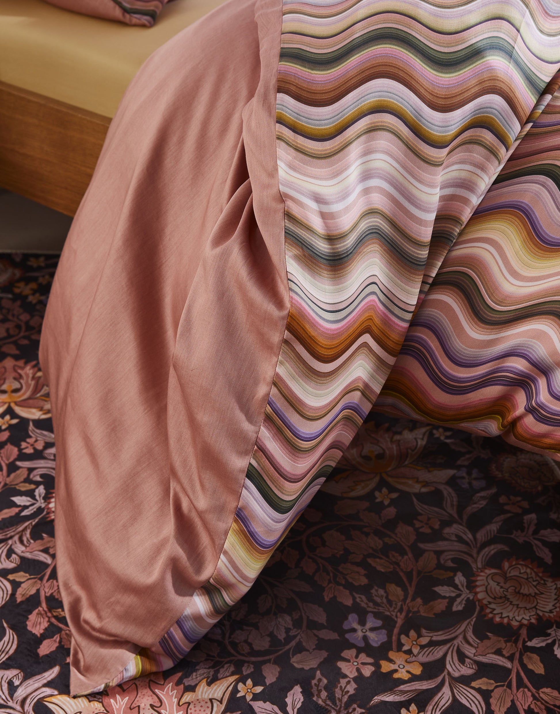 Detaildarstellung auf Kopfkissen und Bettdecke der vertikalen Schlangenlinien der Essenza Satin Bettwaesche Modell Sol Antique Pink.
