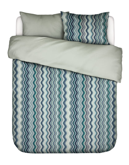 Zwei Kopfkissen und eine Bettdecke bezogen mit Satin Bettwaesche von Essenza mit einem Muster aus vertikalen Schlangenlinien in der Farbe Tuerkis. Modell Sol Comforting Green.