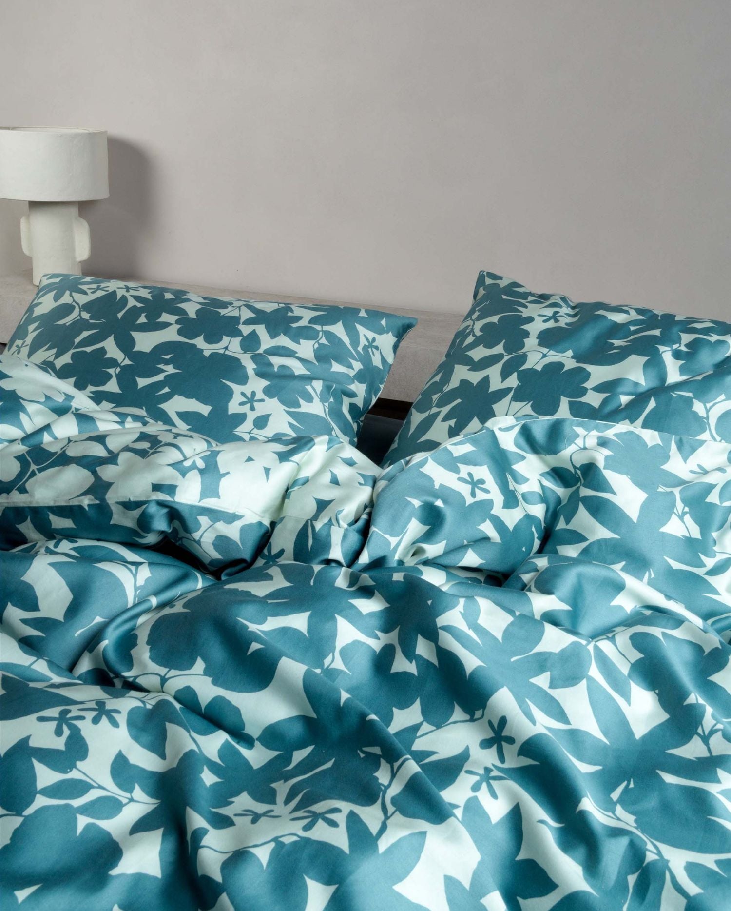 Detaildarstellung auf Kopfkissen und Bettdecke der Essenza Satin Bettwaesche Modell Sora Smoke Blue.