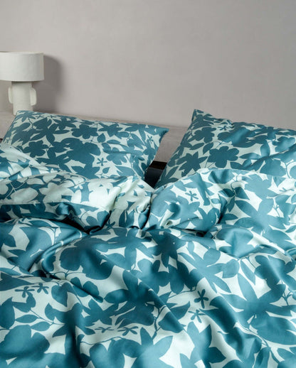 Detaildarstellung auf Kopfkissen und Bettdecke der Essenza Satin Bettwaesche Modell Sora Smoke Blue.
