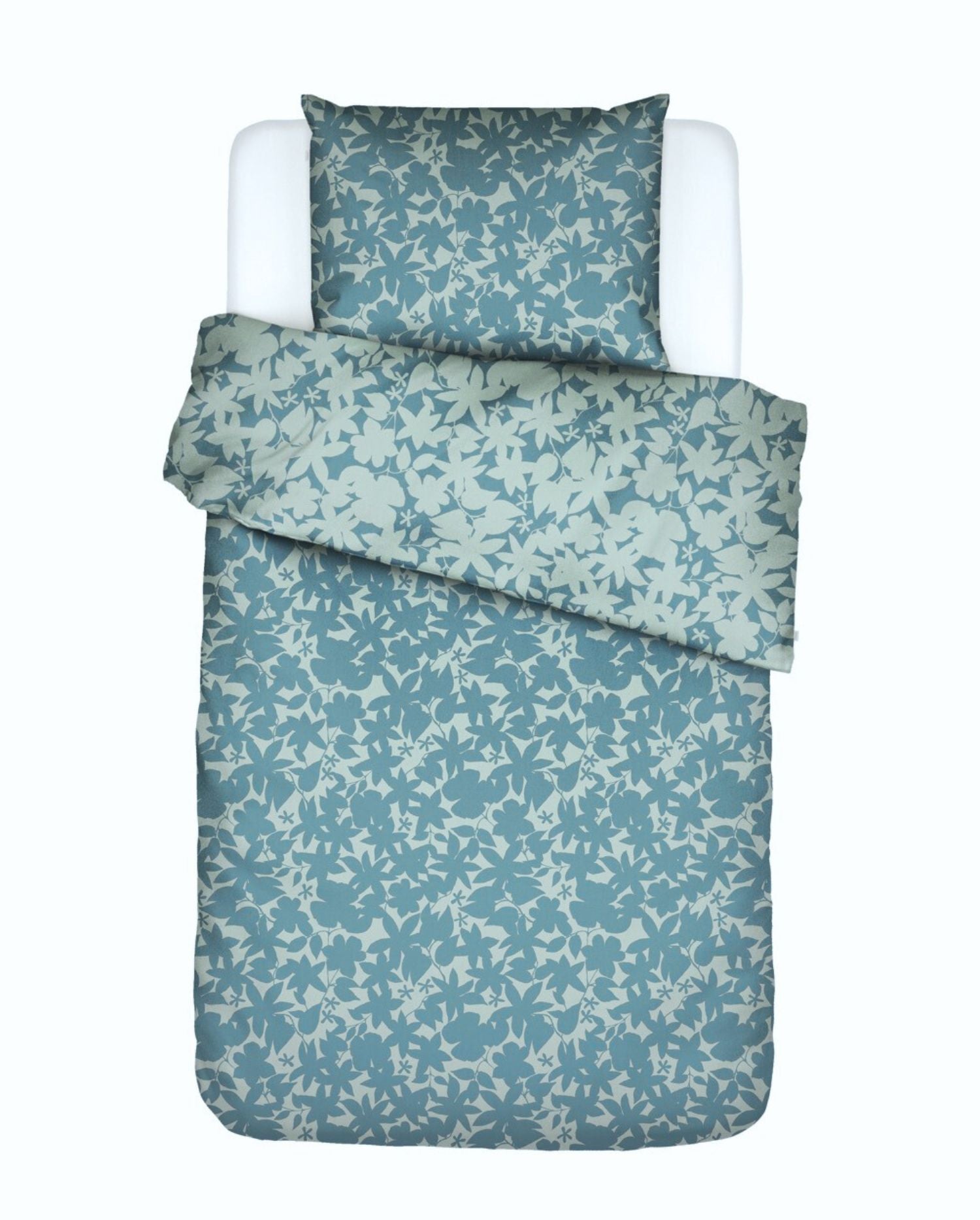 Ein Kopfkissen und eine Bettdecke bezogen mit Satin Bettwaesche von Essenza mit einem Muster aus Blaettern in der Farbe Blau. Modell Sora Smoke Blue.