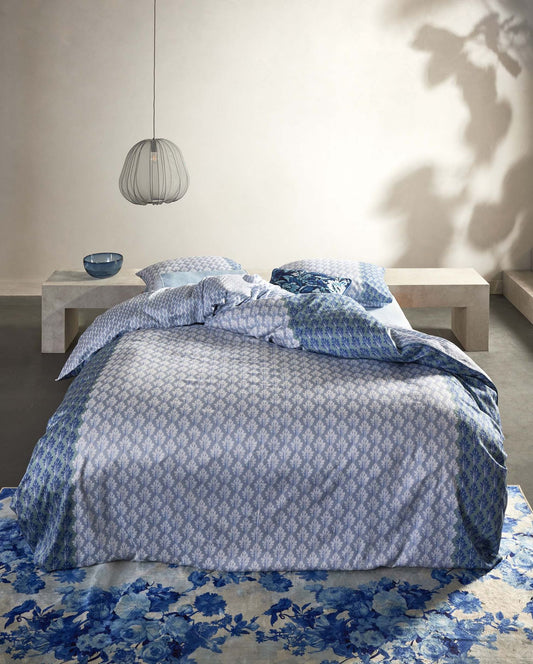 Ein Bettbezug-Set aus mehreren Kopfkissen und einer Bettdecke bezogen mit Satin Bettwaesche aus 100 Prozent Baumwolle mit Muster aus Ornamenten in der Farbe Blau. Modell Tesse Zen Blue.