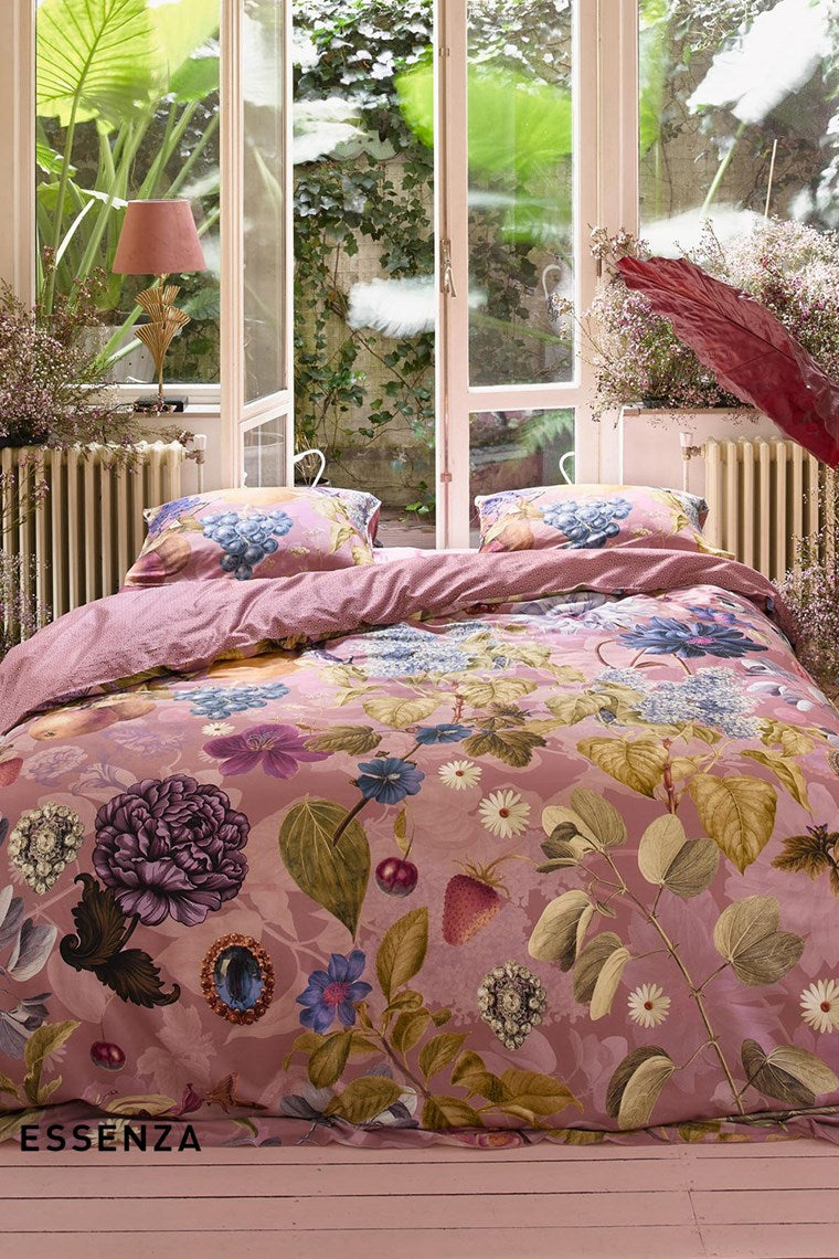 Ein Bettbezug-Set aus mehreren Kopfkissen und einer Bettdecke bezogen mit Satin Bettwaesche aus 100 Prozent Baumwolle mit Muster aus Pflanzen in der Farbe Rosa. Modell Veronique Woodrose.