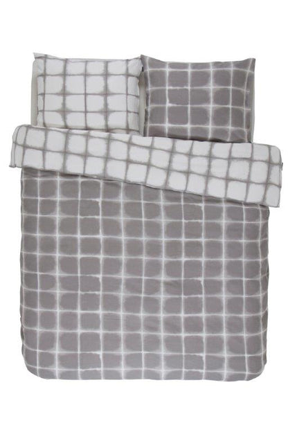 Zwei Kopfkissen und eine Bettdecke bezogen mit Satin Bettwaesche von Essenza mit einem Muster aus Quadraten in der Farbe Silber. Modell Zayn Stone.