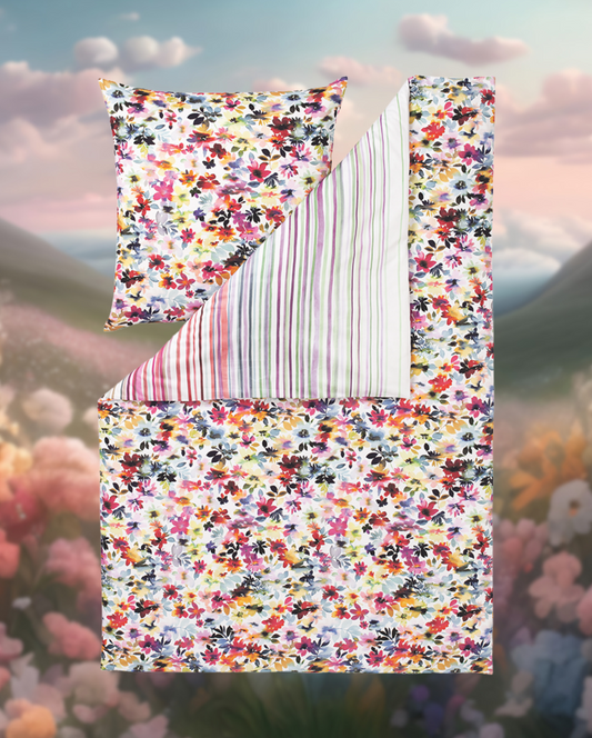 Ein Bettbezug-Set aus mehreren Kopfkissen und einer Bettdecke bezogen mit Satin Bettwaesche aus 100 Prozent Baumwolle mit Muster aus Blumen in der Farbe Mehrfarbig. Modell Mainau.