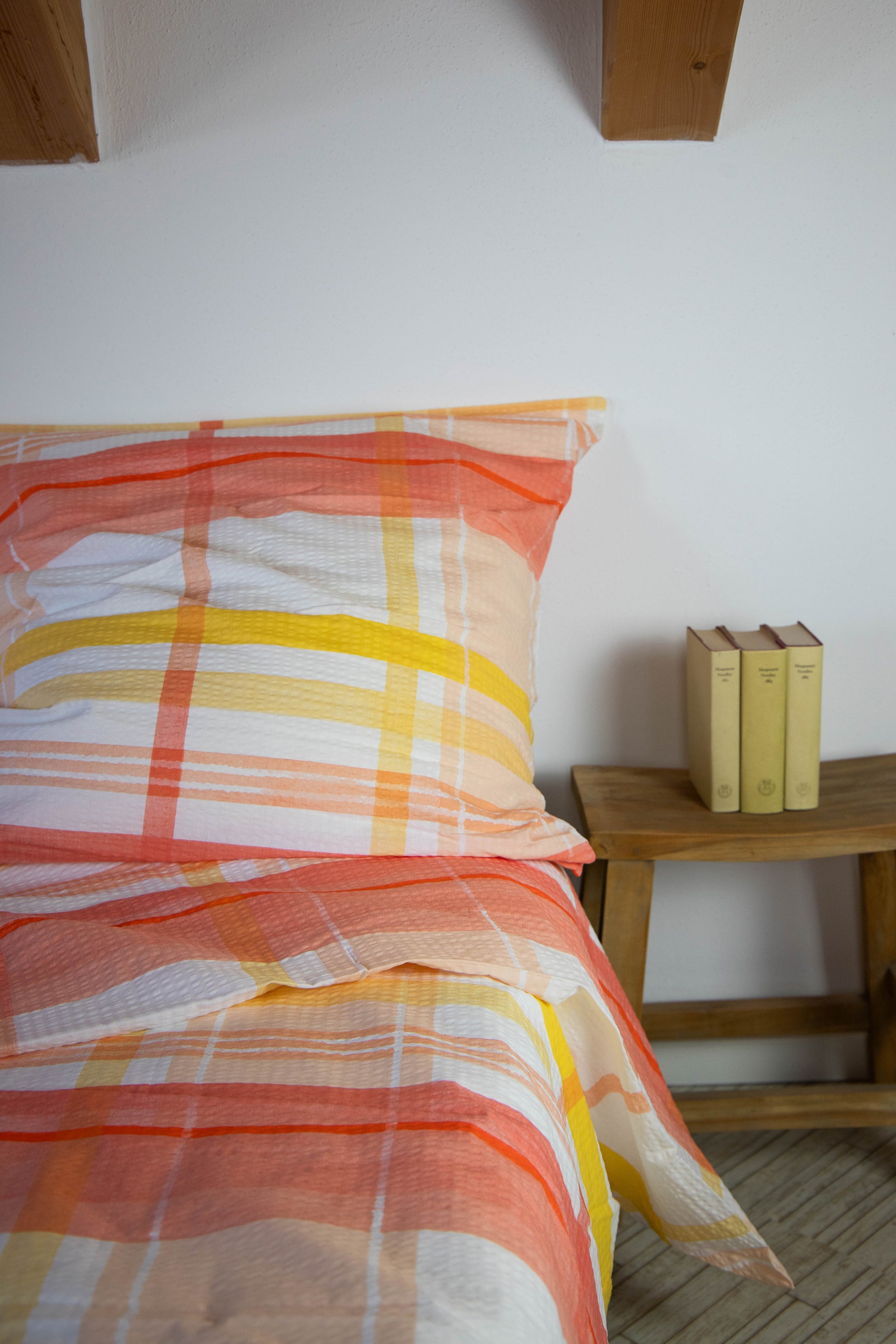 Ein Bettbezug-Set aus einem Kopfkissen und einer Bettdecke bezogen mit Seersucker Bettwaesche aus 100 Prozent Baumwolle mit Karomuster in der Farbe Orange. Modell Karo Orange.