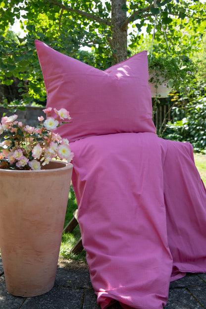 Ein Bettbezug-Set aus einem Kopfkissen und einer Bettdecke bezogen mit Seersucker Bettwaesche aus 100 Prozent Baumwolle in der Farbe Pink. Modell Pink.