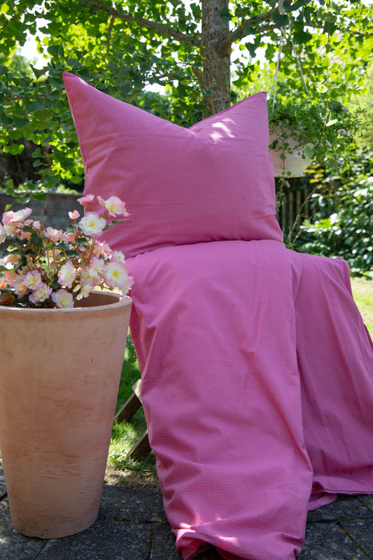 Ein Bettbezug-Set aus einem Kopfkissen und einer Bettdecke bezogen mit Seersucker Bettwaesche aus 100 Prozent Baumwolle in der Farbe Pink. Modell Pink.