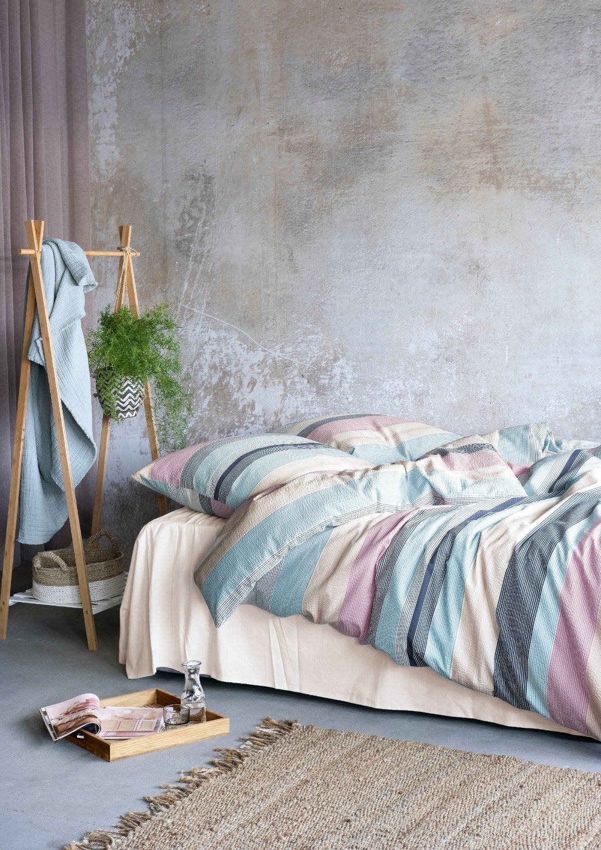 Auf einem Bett liegen mehrere Kopfkissen und eine Bettdecke bezogen mit Soft Seersucker Bettwaesche aus 100 Prozent Baumwolle mit Muster aus horizontalen Streifen in der Farbe Mehrfarbig. Modell Easy Stripes.